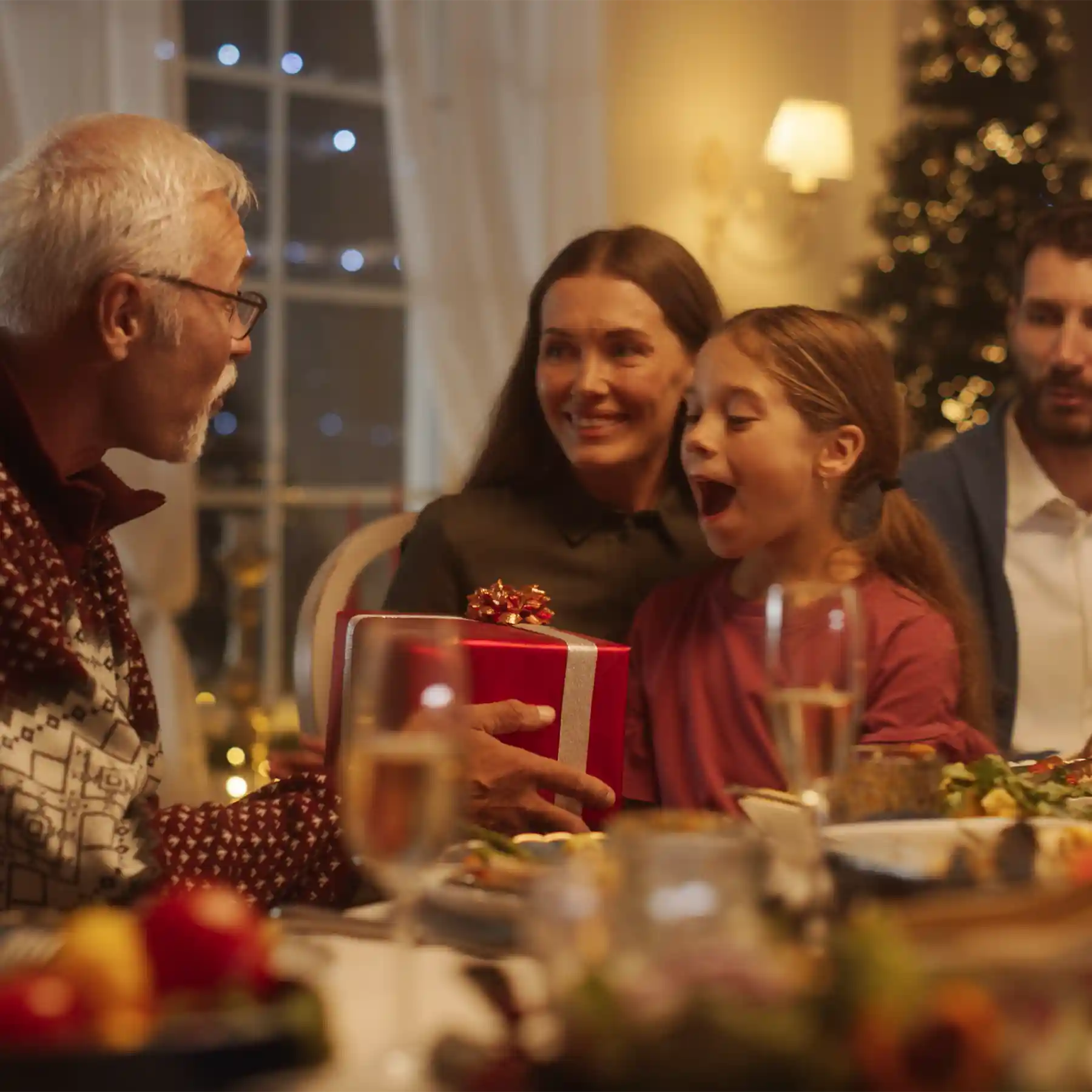 Scene from ad: Grandpa giving a gift to granddaughter during christmas.